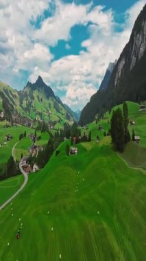 İnsansız hava aracı, arkasında dağlar olan yeşil renkli vadilerin üzerinden uçuyor. Yüksek Dağlar İsviçre 'nin ünlü simgeleridir. İsviçre 'deki Idyllic dağ manzarası, İsviçre kırsal havası.