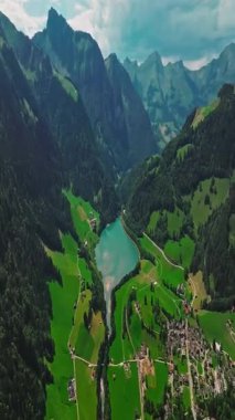 İnsansız hava aracı, arkasında dağlar olan yeşil renkli vadilerin üzerinden uçuyor. Yüksek Dağlar İsviçre 'nin ünlü simgeleridir. İsviçre 'deki Idyllic dağ manzarası, İsviçre kırsal havası.