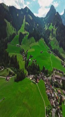 İnsansız hava aracı, arkasında dağlar olan yeşil renkli vadilerin üzerinden uçuyor. Yüksek Dağlar İsviçre 'nin ünlü simgeleridir. İsviçre 'deki Idyllic dağ manzarası, İsviçre kırsal havası.