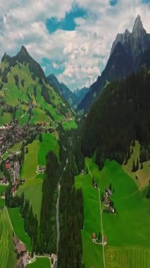 İnsansız hava aracı, arkasında dağlar olan yeşil renkli vadilerin üzerinden uçuyor. Yüksek Dağlar İsviçre 'nin ünlü simgeleridir. İsviçre 'deki Idyllic dağ manzarası, İsviçre kırsal havası.