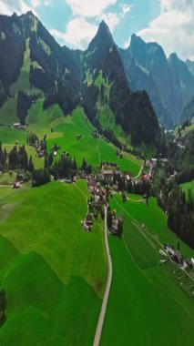 İnsansız hava aracı, arkasında dağlar olan yeşil renkli vadilerin üzerinden uçuyor. Yüksek Dağlar İsviçre 'nin ünlü simgeleridir. İsviçre 'deki Idyllic dağ manzarası, İsviçre kırsal havası.