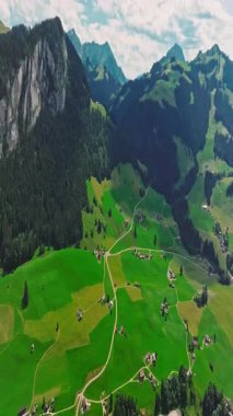 İnsansız hava aracı, arkasında dağlar olan yeşil renkli vadilerin üzerinden uçuyor. Yüksek Dağlar İsviçre 'nin ünlü simgeleridir. İsviçre 'deki Idyllic dağ manzarası, İsviçre kırsal havası.