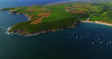 Güzel deniz manzarası, güzel kayalık kıyı, Fransa 'daki insansız hava aracı manzarası. Mavi okyanustaki kayaların üzerinden uçan dalgaların görüntüsü. Körfeze demirlemiş küçük motorlu tekne ve yatlar..