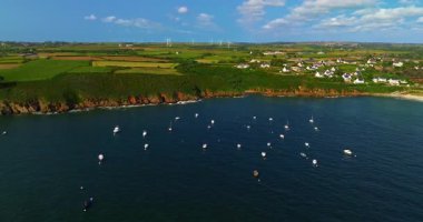 Güzel deniz manzarası, güzel kayalık kıyı, Fransa 'daki insansız hava aracı manzarası. Mavi okyanustaki kayaların üzerinden uçan dalgaların görüntüsü. Körfeze demirlemiş küçük motorlu tekne ve yatlar..