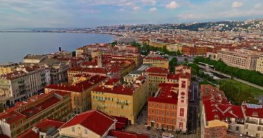 Güneşli bir günde, hareketli bir sahil yürüyüşü manzarası. Nice, Fransa 'da güzel bir manzara. Palmiye ağaçları, eski kasabadaki eski evler gök mavisi deniz ve yeşil tepeler. Fransız Rivierasında yaz.