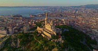 Notre Dame de la Garde 'ın ya da güney Fransa' da günbatımında Muhafız Kilisesi 'nin hava manzarası. Sıcak yaz akşamı ışığı Marsilya şehir manzarasını aydınlatıyor..