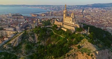 Notre Dame de la Garde 'ın ya da güney Fransa' da günbatımında Muhafız Kilisesi 'nin hava manzarası. Sıcak yaz akşamı ışığı Marsilya şehir manzarasını aydınlatıyor..