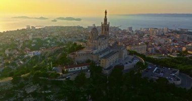 Notre Dame de la Garde 'ın ya da güney Fransa' da günbatımında Muhafız Kilisesi 'nin hava manzarası. Sıcak yaz akşamı ışığı Marsilya şehir manzarasını aydınlatıyor..