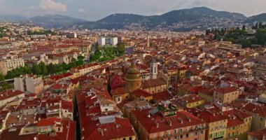 Güneşli bir günde, hareketli bir sahil yürüyüşü manzarası. Nice, Fransa 'da güzel bir manzara. Palmiye ağaçları, eski kasabadaki eski evler gök mavisi deniz ve yeşil tepeler. Fransız Rivierasında yaz.
