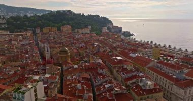 Güneşli bir günde, hareketli bir sahil yürüyüşü manzarası. Nice, Fransa 'da güzel bir manzara. Palmiye ağaçları, eski kasabadaki eski evler gök mavisi deniz ve yeşil tepeler. Fransız Rivierasında yaz.