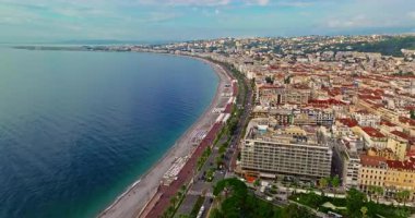 Güneşli bir günde, hareketli bir sahil yürüyüşü manzarası. Nice, Fransa 'da güzel bir manzara. Palmiye ağaçları, eski kasabadaki eski evler gök mavisi deniz ve yeşil tepeler. Fransız Rivierasında yaz.