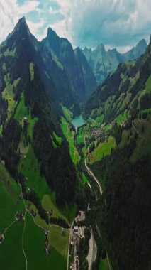 İnsansız hava aracı, arkasında dağlar olan yeşil renkli vadilerin üzerinden uçuyor. Yüksek Dağlar İsviçre 'nin ünlü simgeleridir. İsviçre 'deki Idyllic dağ manzarası, İsviçre kırsal havası.