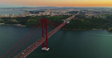 Portekiz, Lizbon 'da gün batımında Tagus Nehri üzerindeki 25 de Abril köprüsünün hava görüntüsü.