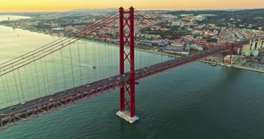 Portekiz, Lizbon 'da gün batımında Tagus Nehri üzerindeki 25 de Abril köprüsünün hava görüntüsü.