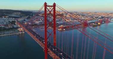 Portekiz, Lizbon 'da gün batımında Tagus Nehri üzerindeki 25 de Abril köprüsünün hava görüntüsü.
