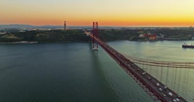 Portekiz, Lizbon 'da gün batımında Tagus Nehri üzerindeki 25 de Abril köprüsünün hava görüntüsü.