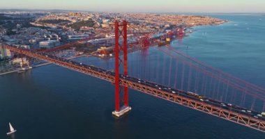 Portekiz, Lizbon 'da gün batımında Tagus Nehri üzerindeki 25 de Abril köprüsünün hava görüntüsü.