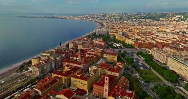Güneşli bir günde, hareketli bir sahil yürüyüşü manzarası. Nice, Fransa 'da güzel bir manzara. Palmiye ağaçları, eski kasabadaki eski evler gök mavisi deniz ve yeşil tepeler. Fransız Rivierasında yaz.