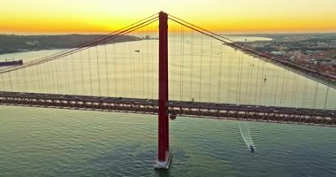 Portekiz, Lizbon 'da gün batımında Tagus Nehri üzerindeki 25 de Abril köprüsünün hava görüntüsü.