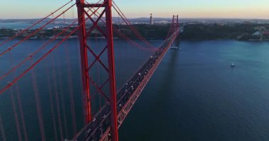 Portekiz, Lizbon 'da gün batımında Tagus Nehri üzerindeki 25 de Abril köprüsünün hava görüntüsü.
