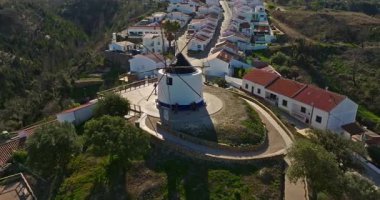 Yel değirmeni ve pitoresk çatıları olan küçük köyün havadan görünüşü, Aldatmaca, Portekiz.