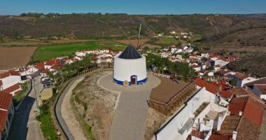 Yel değirmeni ve pitoresk çatıları olan küçük köyün havadan görünüşü, Aldatmaca, Portekiz.