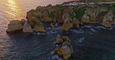 Günbatımında Ponta da Piedade, Lagos, Portekiz 'deki dramatik uçurumların ve deniz fenerinin havadan görünüşü.