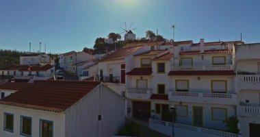 Yel değirmeni ve pitoresk çatıları olan küçük köyün havadan görünüşü, Aldatmaca, Portekiz.