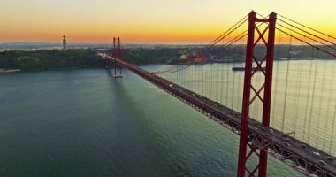 Portekiz, Lizbon 'da gün batımında Tagus Nehri üzerindeki 25 de Abril köprüsünün hava görüntüsü.