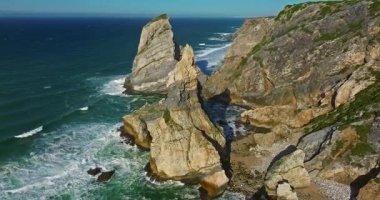 Büyük kayalıkların üzerine köpüklü dalgaların düştüğü Ursa sahili Atlantik sahil sörfü. Portekiz.