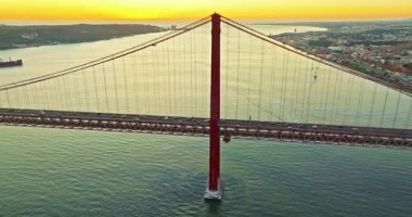 Portekiz, Lizbon 'da gün batımında Tagus Nehri üzerindeki 25 de Abril köprüsünün hava görüntüsü.