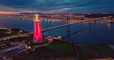 Lizbon 'daki Kral İsa' nın günbatımında Lizbon, Portekiz 'de katolik anıtı üzerindeki hava görüşü. Gece ya da akşam Sığınak 'ın kırmızı arka planı ve güzel bir akşam manzarası.