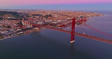 Portekiz, Lizbon 'da gün batımında Tagus Nehri üzerindeki 25 de Abril köprüsünün hava görüntüsü.