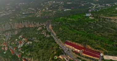 Monako ve çevresindeki şehirler arasında uzanan yolun hava görüntüsü dağların içinden geçiyor..