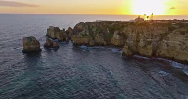 Günbatımında Ponta da Piedade, Lagos, Portekiz 'deki dramatik uçurumların ve deniz fenerinin havadan görünüşü.