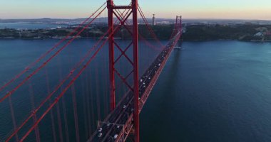 Portekiz, Lizbon 'da gün batımında Tagus Nehri üzerindeki 25 de Abril köprüsünün hava görüntüsü.