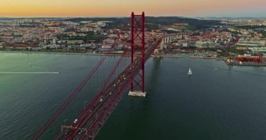 Portekiz, Lizbon 'da gün batımında Tagus Nehri üzerindeki 25 de Abril köprüsünün hava görüntüsü.