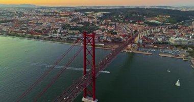 Portekiz, Lizbon 'da gün batımında Tagus Nehri üzerindeki 25 de Abril köprüsünün hava görüntüsü. 