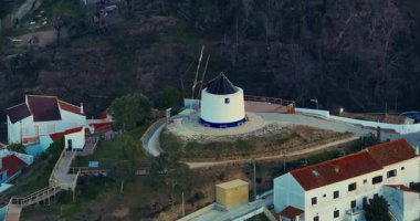 Yel değirmeni ve pitoresk çatıları olan küçük köyün havadan görünüşü, Aldatmaca, Portekiz.