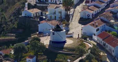 Yel değirmeni ve pitoresk çatıları olan küçük köyün havadan görünüşü, Aldatmaca, Portekiz.