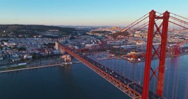 Portekiz, Lizbon 'da gün batımında Tagus Nehri üzerindeki 25 de Abril köprüsünün hava görüntüsü.