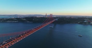 Portekiz, Lizbon 'da gün batımında Tagus Nehri üzerindeki 25 de Abril köprüsünün hava görüntüsü.