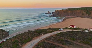 Gün batımında okyanus dalgalarının kumlu kıyı şeridi havadan görüntüsü. Dalgalar okyanusu okşar, güzel okyanus kıyıları Portekiz 'i.