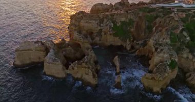 Günbatımında Ponta da Piedade, Lagos, Portekiz 'deki dramatik uçurumların ve deniz fenerinin havadan görünüşü.