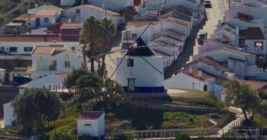 Yel değirmeni ve pitoresk çatıları olan küçük köyün havadan görünüşü, Aldatmaca, Portekiz.