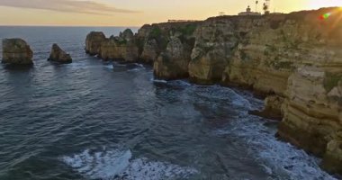 Günbatımında Ponta da Piedade, Lagos, Portekiz 'deki dramatik uçurumların ve deniz fenerinin havadan görünüşü.