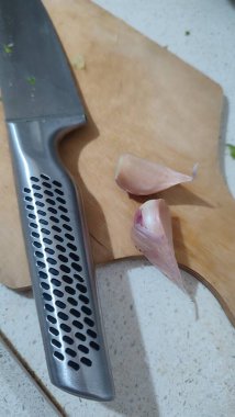 Alüminyum bıçak, mutfak tahtası, sarımsak karanfili, yemek pişirme. Yüksek kalite fotoğraf