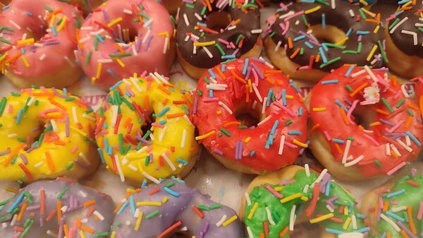  Colorful sprinkled donuts ,round donut sufganiyot pastries sweet dessert, food in bakery, Hanukkah holiday culinary traditions. High quality photo
