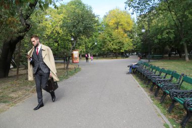 12 Ekim 2022 Bükreş, Romanya, başkent caddesi, yeşil dinlenme parkı, banklar, işadamları sonbahar gezisi, turistler için ahşap tabela, doğa seyahati geliyor.