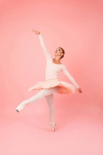 穿着燕尾服和尖鞋的年轻女子的全长肖像在粉色背景下练习芭蕾舞 恩典和艺术的概念 — 图库照片